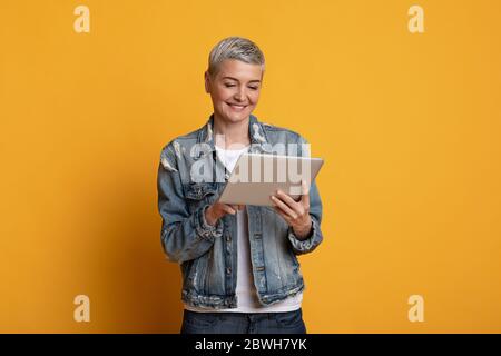 Great App. Beautiful middle-aged woman in stylish clothes using digital tablet Stock Photo