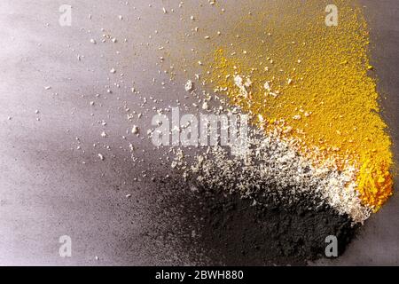 Colorful explosion of three ingredients: activated carbon, coconut and turmeric on grey background Stock Photo