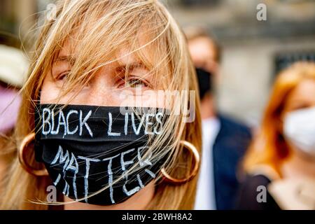 A young woman, is seen wearing a black mask with writings reading "Black Lives matter" during the protest at Dam Square.Thousands of people take part in "Black Lives Matter" protest held at Dam Square in Amsterdam, to protest against the recent killing of George Floyd, a black man who died in police custody in Minneapolis, U.S.A., after being restrained by Minneapolis police officers on Memorial Day. Stock Photo