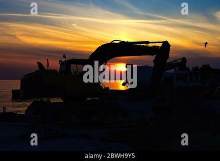 Silhouette Earth Mover On Land Against Sky During Sunset Stock Photo