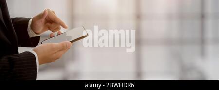 Businessman touching on blank screen smartphone with blurred office background Stock Photo