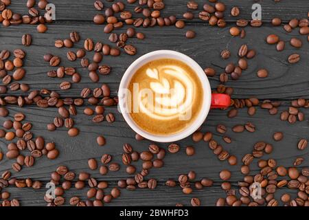 Cup of tasty cappuccino and coffee beans on wooden background Stock Photo
