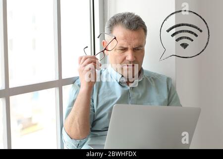 Mature man with laptop using wifi at home Stock Photo