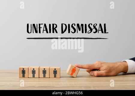 Businessman removing wooden cube with drawn human figure from table. Concept of unfair dismissal Stock Photo