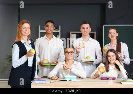 Pupils and teacher having lunch in classroom Stock Photo