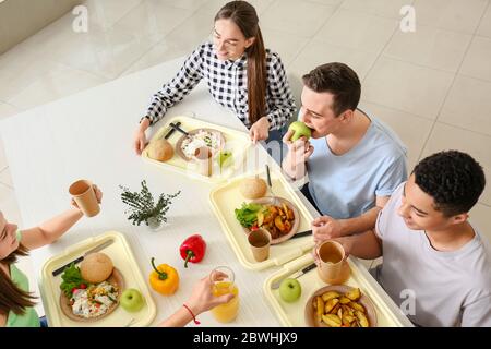 multiethnic kids having lunch in school canteen near teacher smiling on  blurred background Stock Photo - Alamy