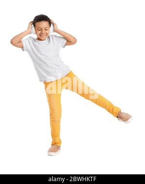 Little African-American boy listening to music and dancing against white background Stock Photo