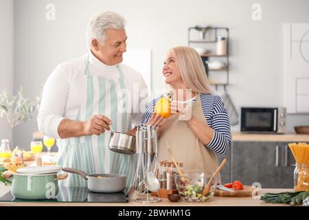 Happy elderly couple cooking in kitchen Stock Photo