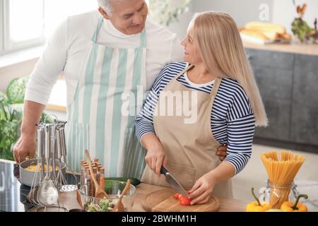 Happy elderly couple cooking in kitchen Stock Photo