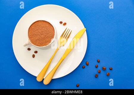 Plate with chocolate cake in shape of coffee cup on color background Stock Photo