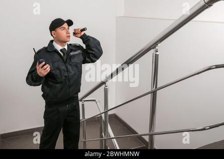 Male security guard with flashlight in building Stock Photo