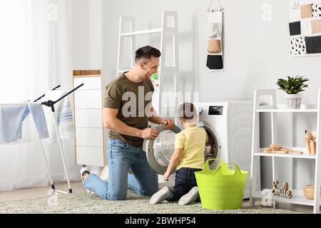Man and his little son doing laundry at home Stock Photo