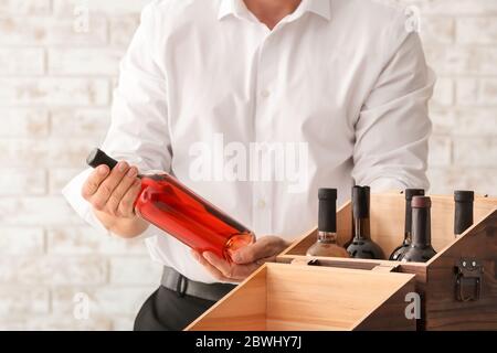 Man with bottles of wine in box on brick background Stock Photo