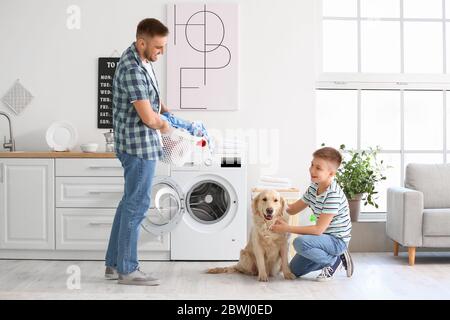 Man and his little son with cute dog doing laundry at home Stock Photo