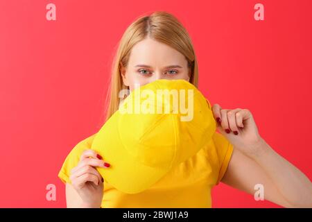 Beautiful young woman with stylish cap on color background Stock Photo