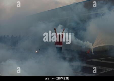 Beijing, USA. 30th May, 2020. A woman raises her arms as riot police fire tear gas during a protest outside the 5th Police Precinct in Minneapolis, the United States, May 30, 2020. Credit: Angus Alexander/Xinhua/Alamy Live News Stock Photo