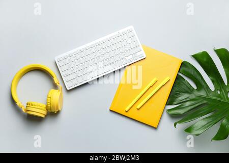 Computer keyboard with notebook, headphones and pens on light background Stock Photo