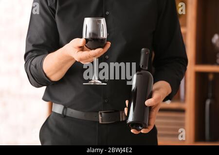 Man with bottle and glass of tasty wine in cellar Stock Photo