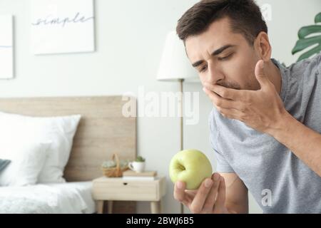 Young man suffering from anorexia with apple at home Stock Photo