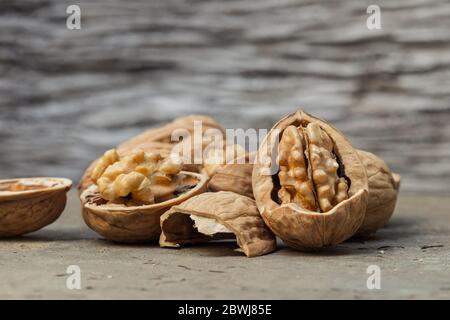 still life with Walnut kernels and whole walnuts on rustic old wooden table. Stock Photo