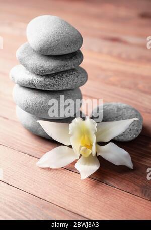 Stack of spa stones and flower on wooden background Stock Photo