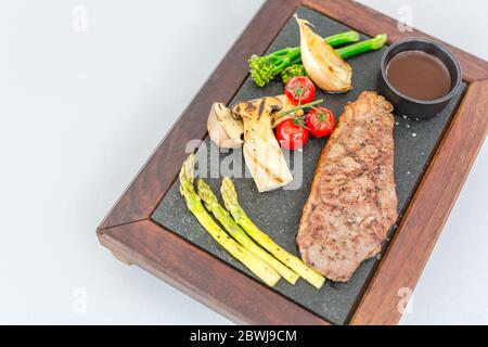 Grilled beef steak meat with vegetables on wooden plate. Luxury beef steak on white background. Beef steak ready for serving Stock Photo