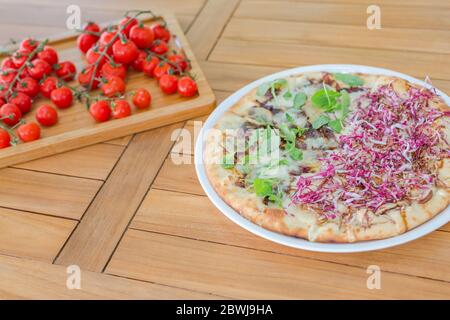 Vegan pizza and fresh vegetables on wooden table Stock Photo