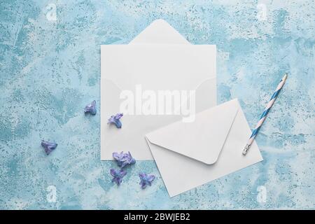 Composition with blank card, envelopes and flowers on color background Stock Photo