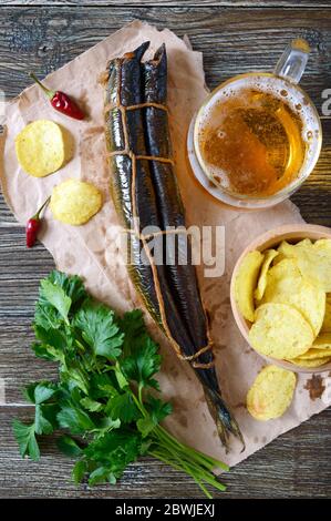 Beer snacks. Smoked fish, chips, a glass of lager beer on a wooden table Stock Photo