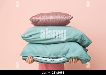Woman with soft pillows on color background Stock Photo