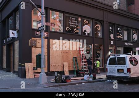 New York, NY, USA - June 1, 2020: Workers board up the Nespresso coffee shop windows on Prince Street in New York City after 2 nights of looting Stock Photo