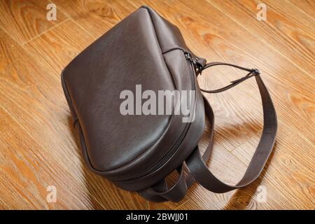 Leather backpack or satchel made of brown leather on a wooden background. Stock Photo