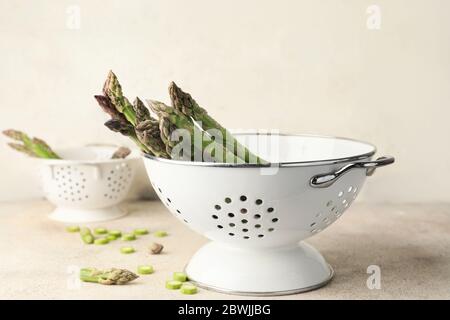 Fresh asparagus in colander on table Stock Photo