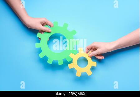 Hands with paper gears on color background. Unity concept Stock Photo