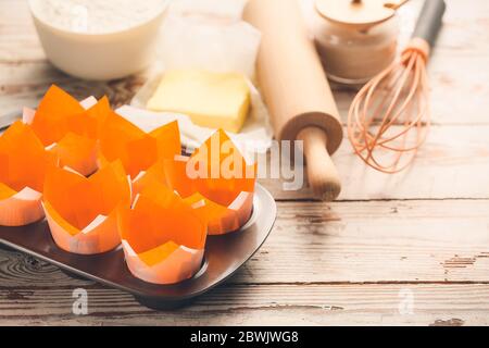 Muffin baking cups with products and utensils on white wooden background Stock Photo