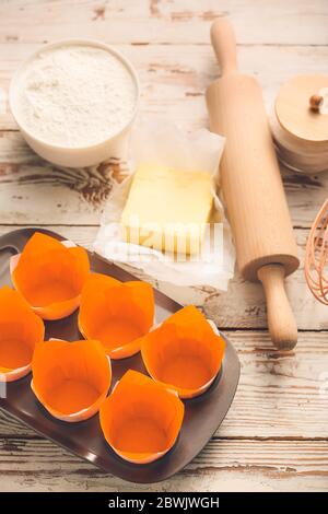 Muffin baking cups with products and utensils on white wooden background Stock Photo