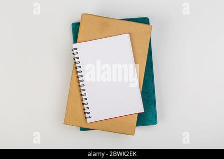 a stack of several spiral school notebooks lies on a white table with a pencil, office concept Stock Photo