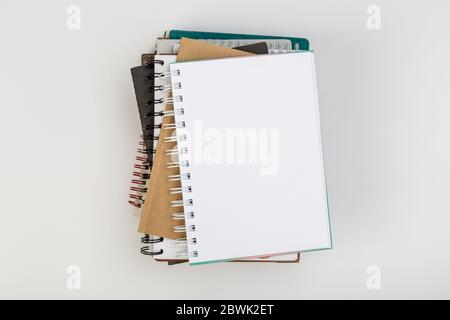 a stack of several spiral school notebooks lies on a white table with a pencil, office concept Stock Photo