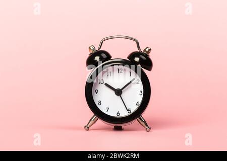black retro alarm clock on a pink background, concept of time, daily routine. ten hours 10 minutes Stock Photo