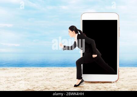 Asian businesswoman running from the phone screen. Digital Detox Concept Stock Photo