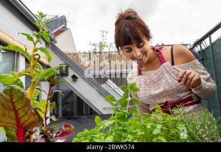A happy young caucasian woman working at the garden in the balcony while smoking a cigarette Stock Photo