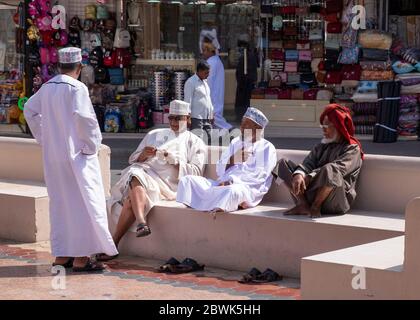 Group of local old men sitting on a bench in the Mutrah Souq, Muscat, Sultanate of Oman. Stock Photo