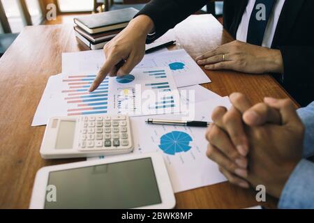 Two businessmen are working analyzing the company annual budget and using digital tablet to find information data result. Stock Photo