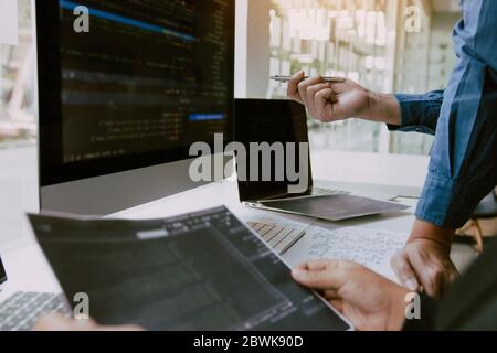 Two partnerships developing programming and coding technologies working on laptop and analyzing together. Stock Photo