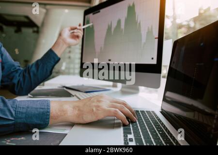 Close up of hand investors are pointing to laptop computer that have investment information stock markets and partners taking notes and analyzing perf Stock Photo
