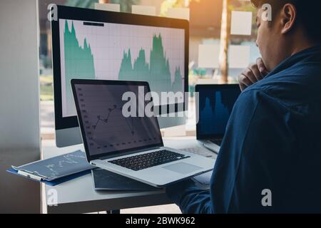 Investors are using laptops entering investment websites stocks market and partners are taking notes and analyzing performance data. Stock Photo
