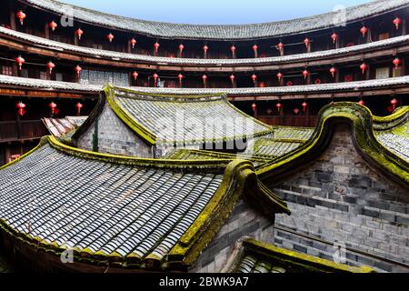 View on the inner structures of a Fujian Tulou: several small houses made of bricks with moss-covered roofs. Stock Photo