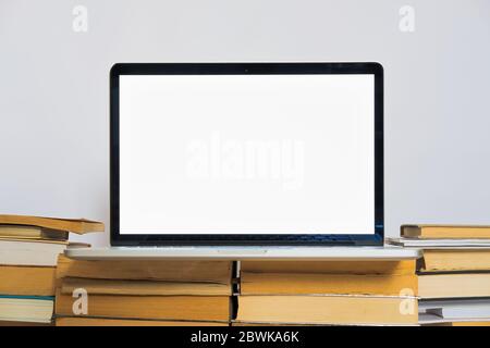 Laptop computer with white screen on the stack of old books. Old versus new technology and education means Stock Photo