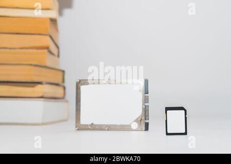Stack of books, hard disk drive and memory card, improving technology. Storage data, compressed information, digital versus analog concept Stock Photo