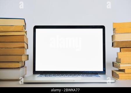 Laptop computer with white screen on the stack of old books. Old versus new technology and education means Stock Photo